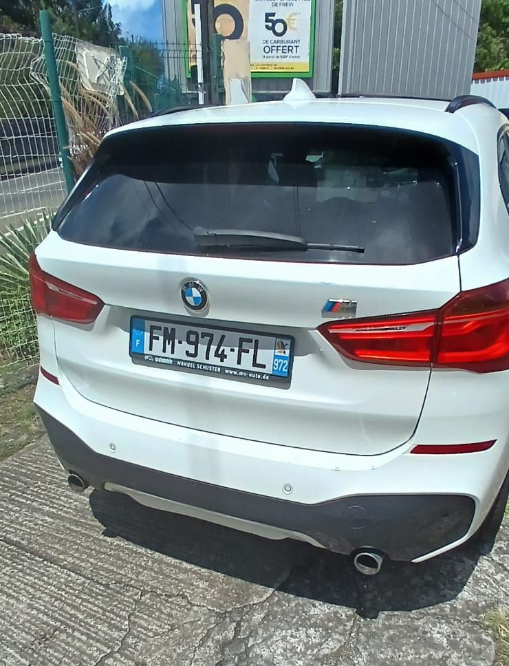 Un SUV BMW blanc garé à l'extérieur, la vue arrière montrant une plaque d'immatriculation française.