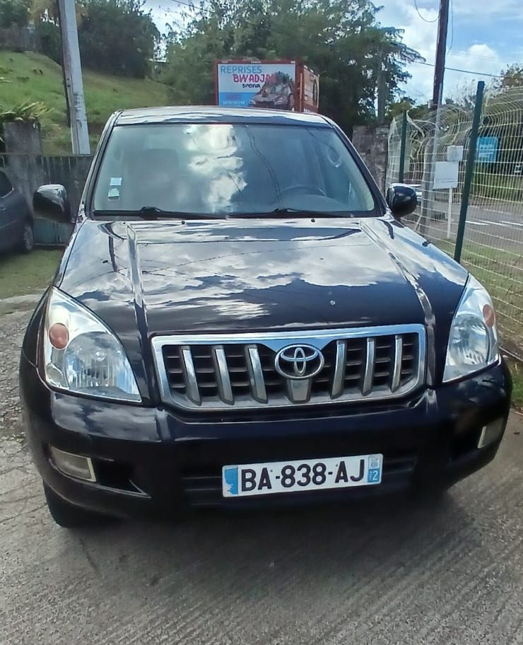 Un Toyota Land Cruiser noir garé sur une route asphaltée sous un ciel nuageux.