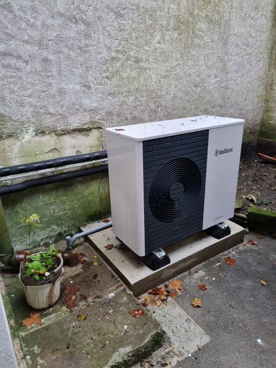 Unité de climatisation blanche sur une terrasse ensoleillée avec des plantes.