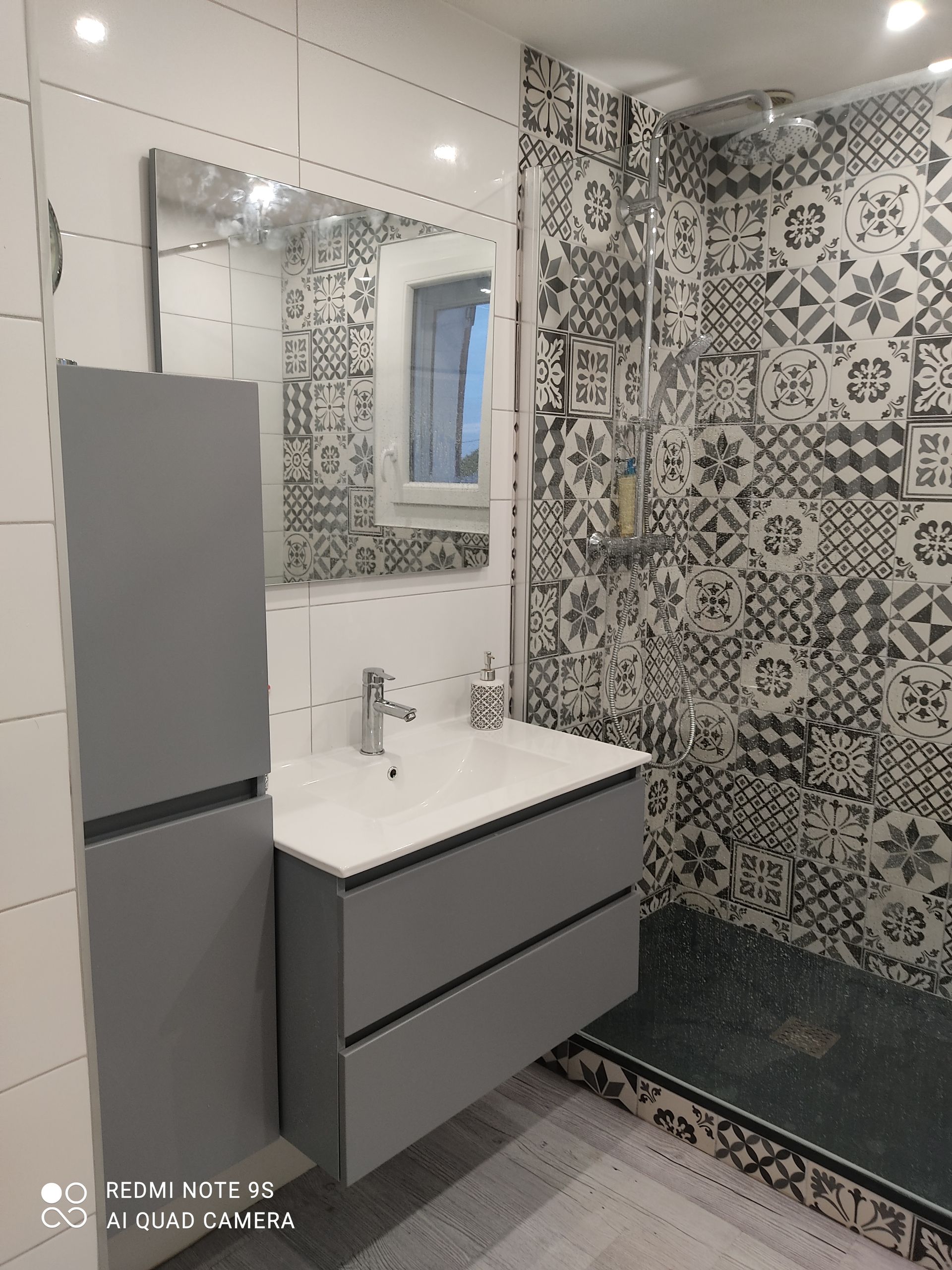 Baignoire en porcelaine blanche, étagère intégrée avec articles de toilette et serviette moelleuse. Base et parois latérales carrelées en bleu.