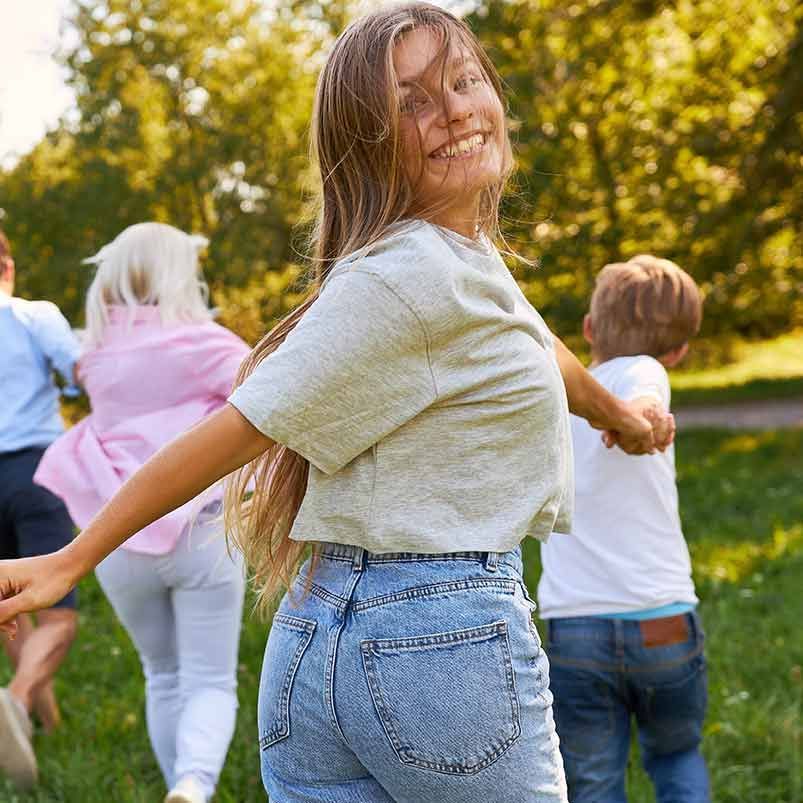 Eine Frau hält in einem Park die Hände zweier Kinder.
