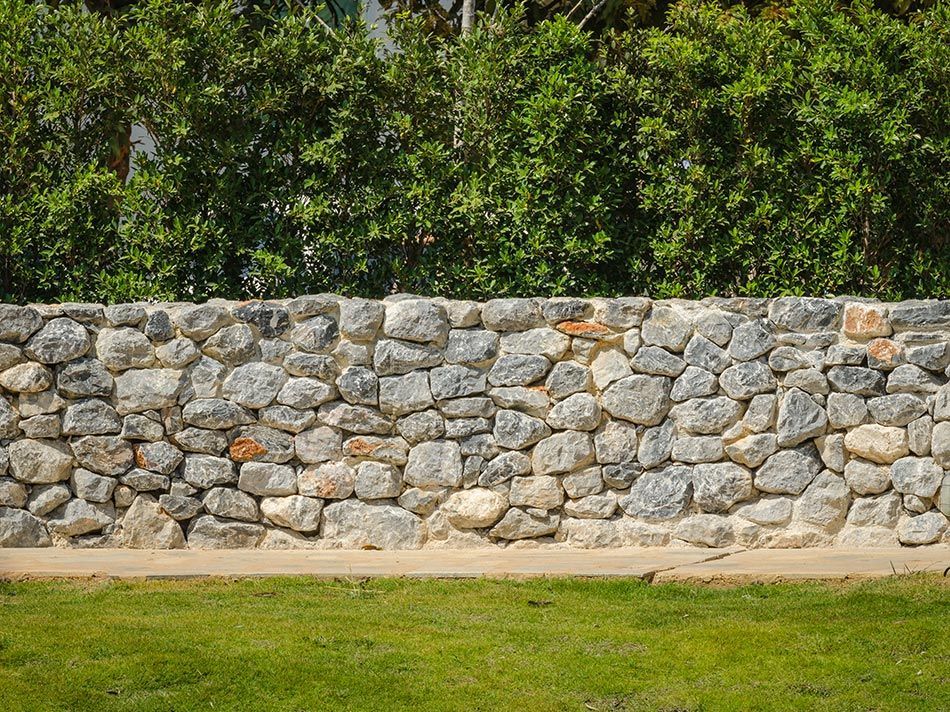Muret en pierre clôturant le terrain d'une maison