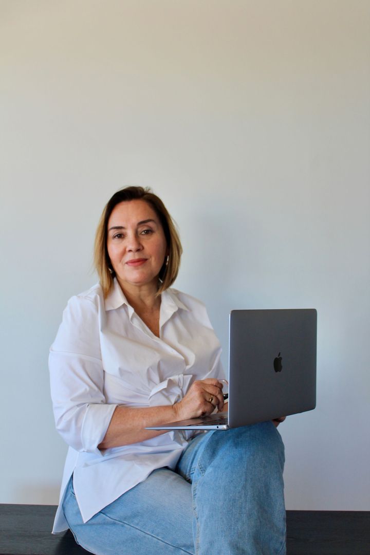 Una mujer que lleva gafas sostiene una computadora portátil.