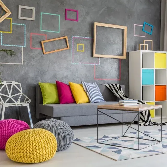Sala de estar con sofá gris, almohadas de colores y arte de pared enmarcado.