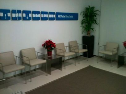 Una sala de espera con sillas blancas y una planta.