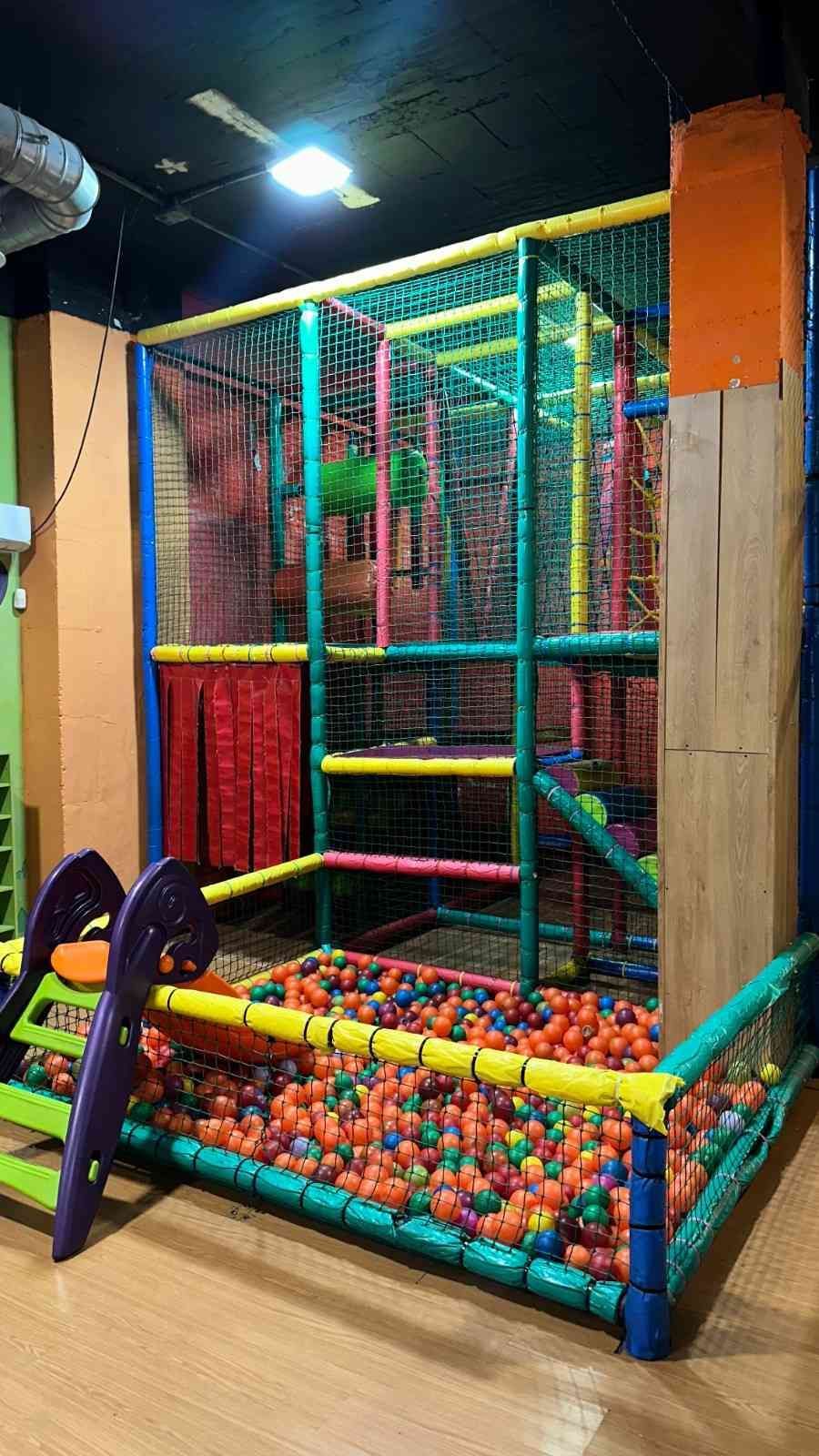 Estructura de juegos infantiles interior con coloridas redes, piscina de bolas y zona de escalada.