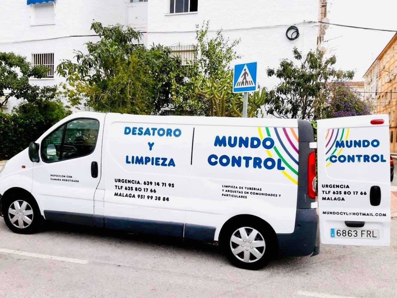 Furgoneta blanca de servicio con el texto azul “Mundo Control” y “Desatoro y Limpieza” estacionada en una calle