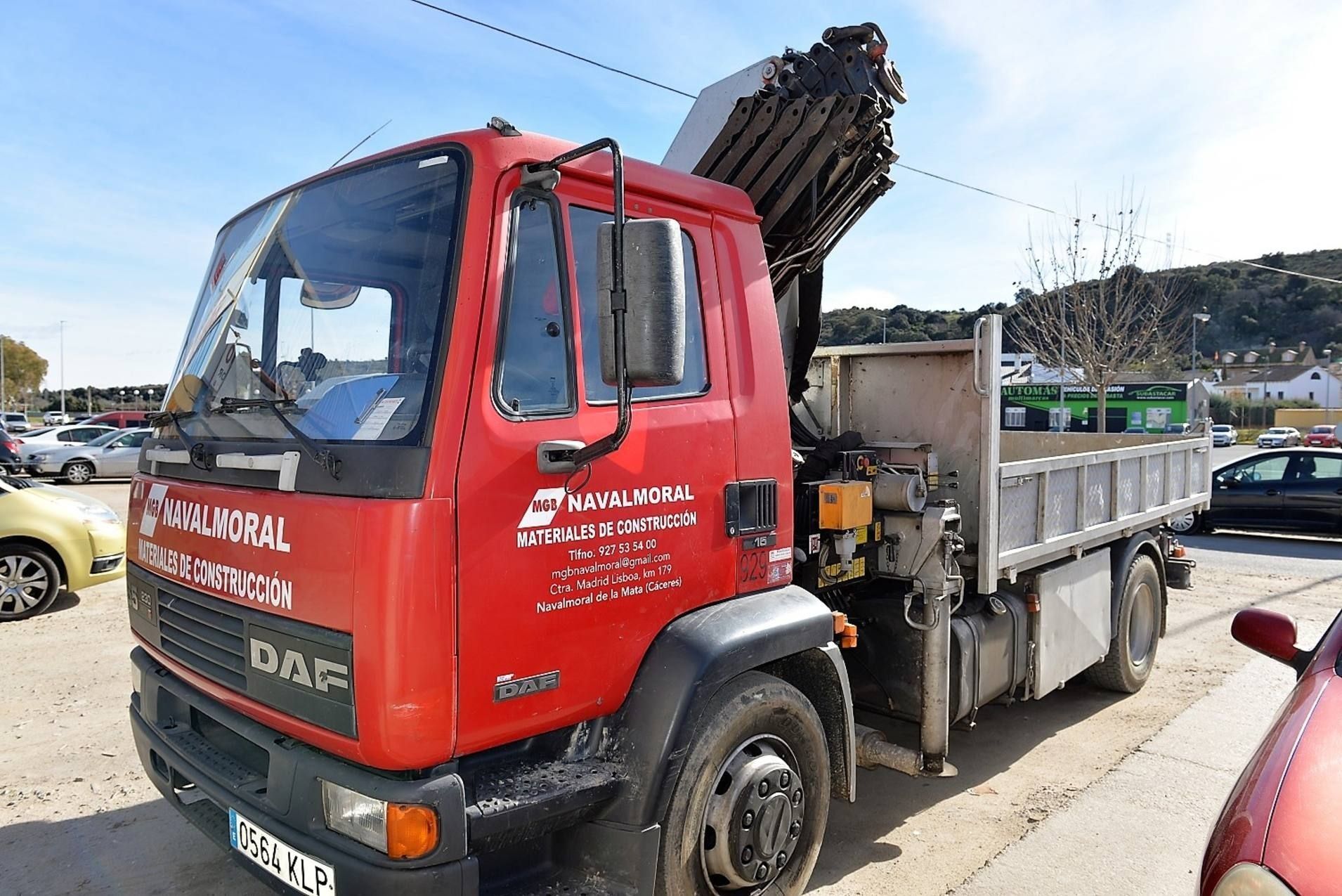 Un camión rojo con una grúa en la parte trasera está estacionado en un estacionamiento.