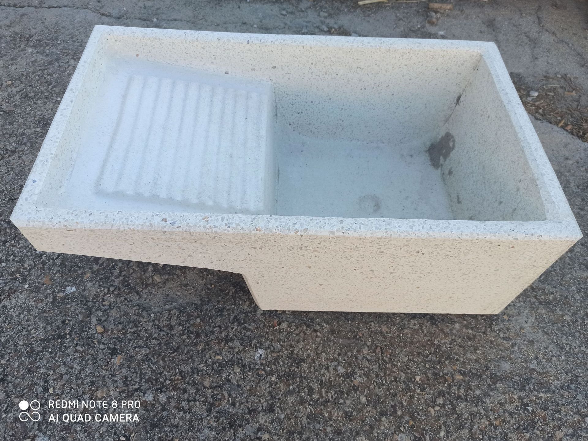 En el suelo hay un fregadero de hormigón con desagüe.