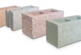 Una fila de bloques de hormigón de diferentes colores están colocados uno al lado del otro sobre una superficie blanca.