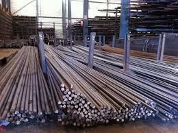 Un montón de barras de metal están apiladas una encima de otra en un almacén.