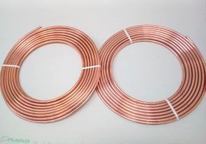 Dos rollos de tubo de cobre están uno al lado del otro sobre una superficie blanca.