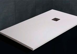 Un plato de ducha blanco está sobre una superficie negra en un baño.