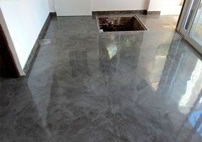 Un suelo de hormigón brillante con un lavabo en el centro de la habitación.