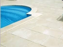 Una piscina de agua azul y suelo de baldosas blancas.