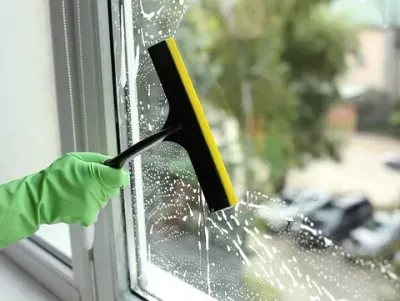 Una persona está limpiando una ventana con una escobilla de goma.