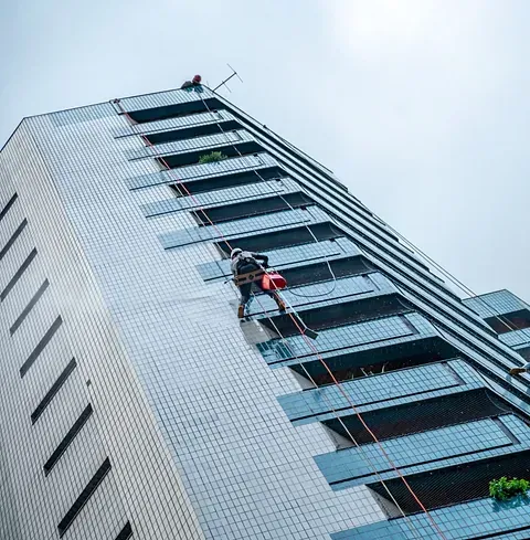 Un hombre está subiendo por el costado de un edificio alto.
