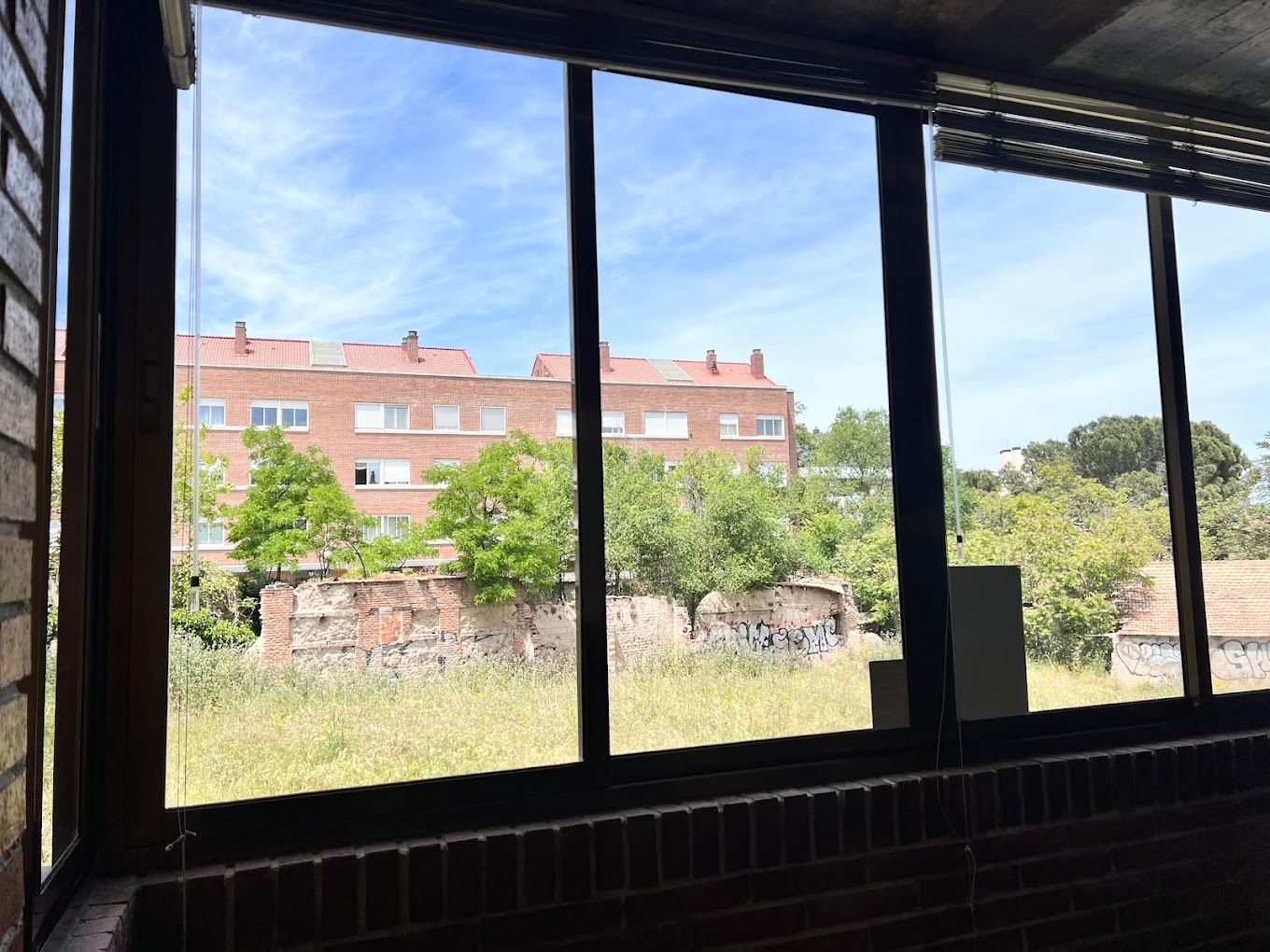 Una gran ventana con vista a un edificio de ladrillo y un campo.