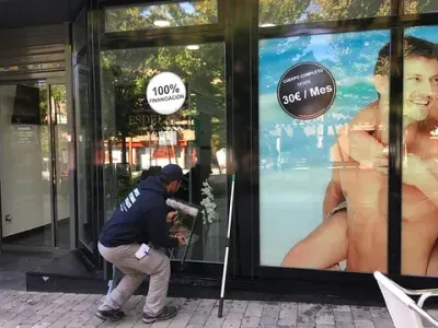 Un hombre está limpiando el escaparate de una tienda con un bastón.