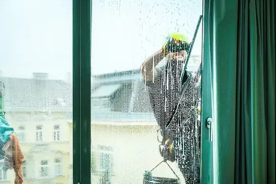 Un hombre está limpiando una ventana con una esponja.
