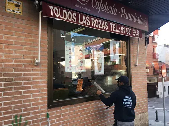 Un hombre está limpiando una ventana de una cafetería.