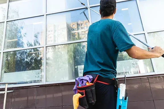 Un hombre está limpiando las ventanas de un edificio con una escobilla de goma.