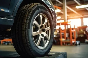 Neumático de automóvil en un elevador de automóviles en un garaje, mostrando el neumático y la rueda.