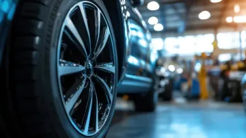 Primer plano de una rueda de coche en un garaje. Rueda negra y plateada brillante con neumático; interior borroso al fondo.