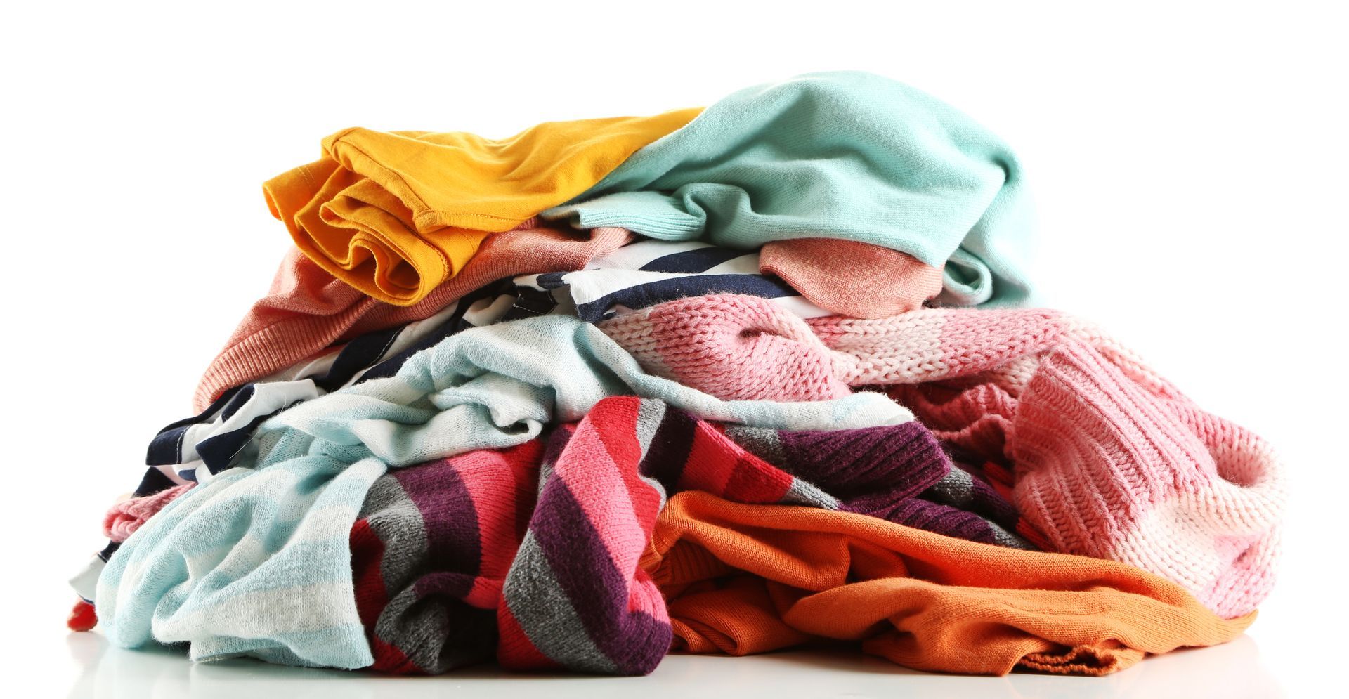 Un tas coloré et désordonné de pulls et de vêtements en tricot dans des tons de jaune, bleu, rose et orange.