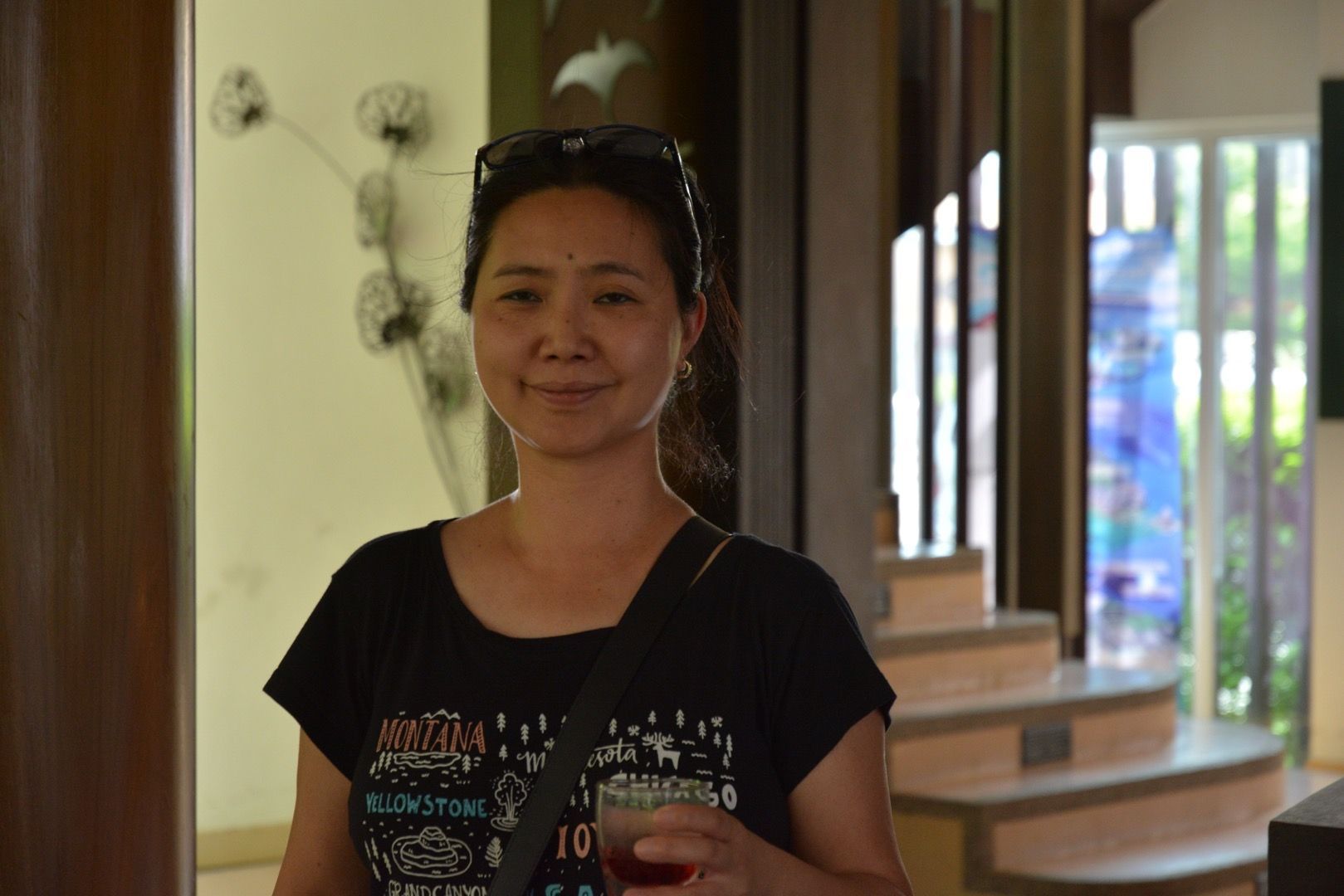 Eine Frau in einem schwarzen Hemd hält ein Glas Wein.