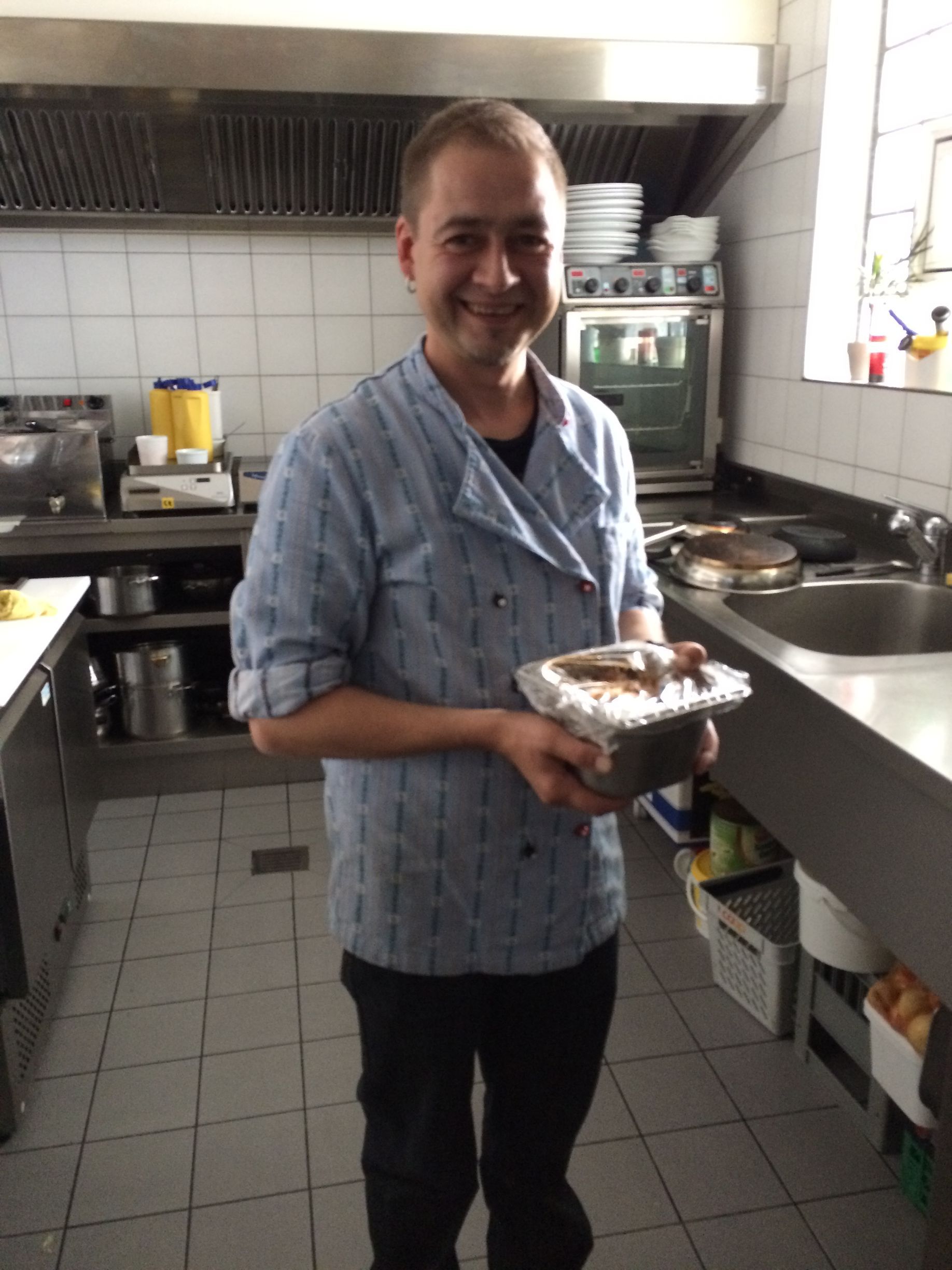 Ein Mann in einer Küche, der einen Behälter mit Essen hält