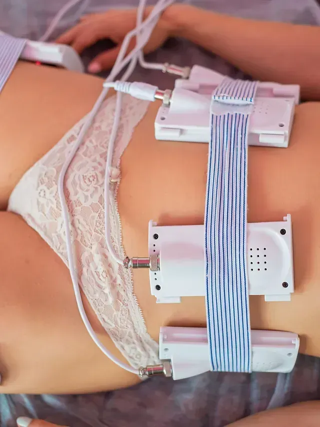 Torso de una persona con electrodos adheridos, vestida con ropa interior de encaje blanco, sometiéndose a un tratamiento de escultura corporal.