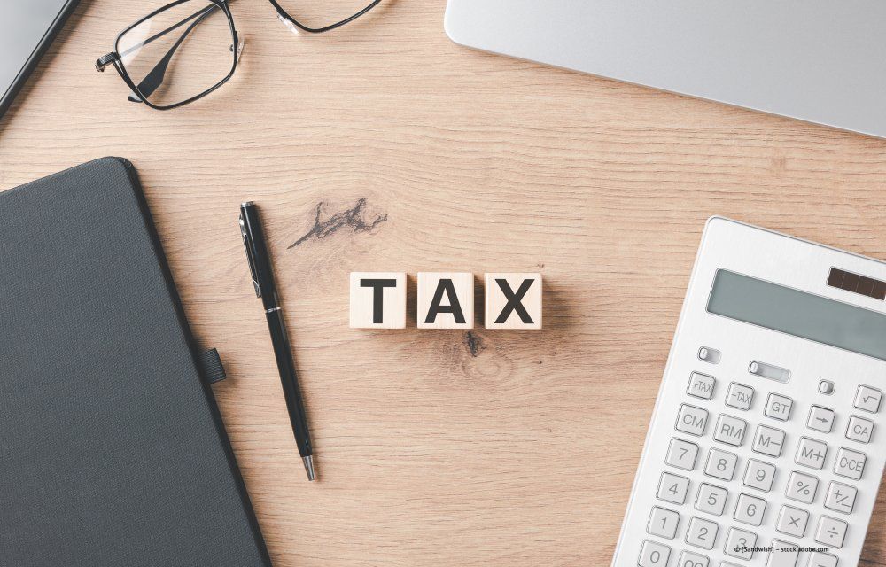 Menschen arbeiten gemeinsam an einem Schreibtisch, benutzen Laptops, Papier und Taschenrechner und besprechen ihre Arbeit.