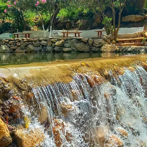 Una cascada está rodeada de rocas y árboles en un parque.