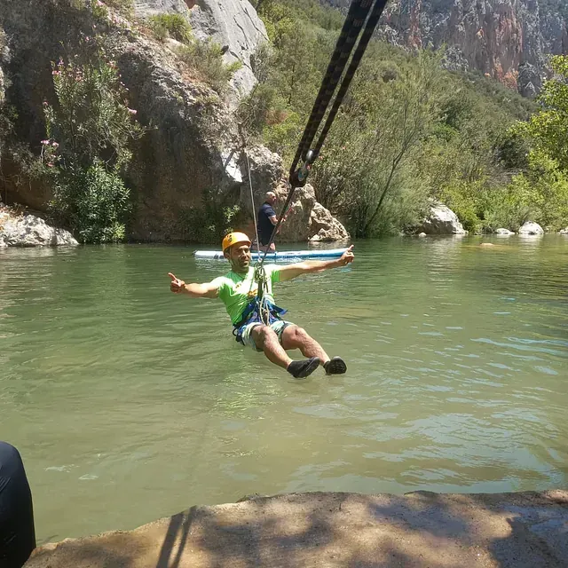 Un hombre está montado en una tirolina sobre un cuerpo de agua.