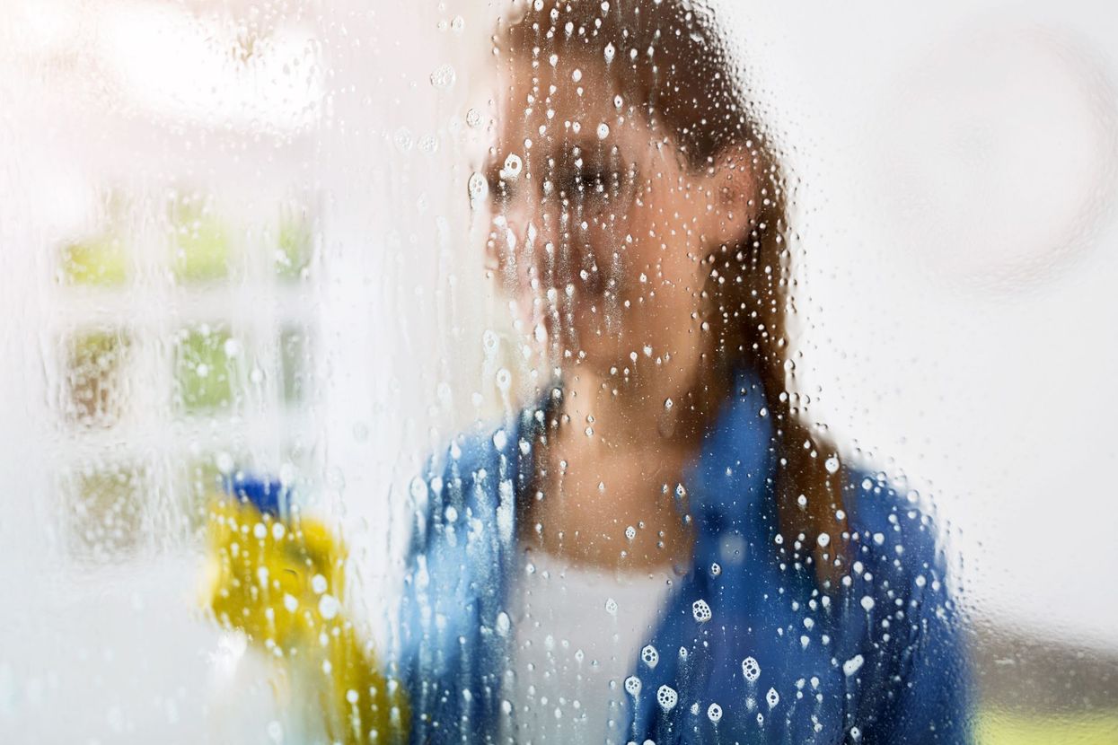 Una mujer está limpiando una ventana con una botella de spray.