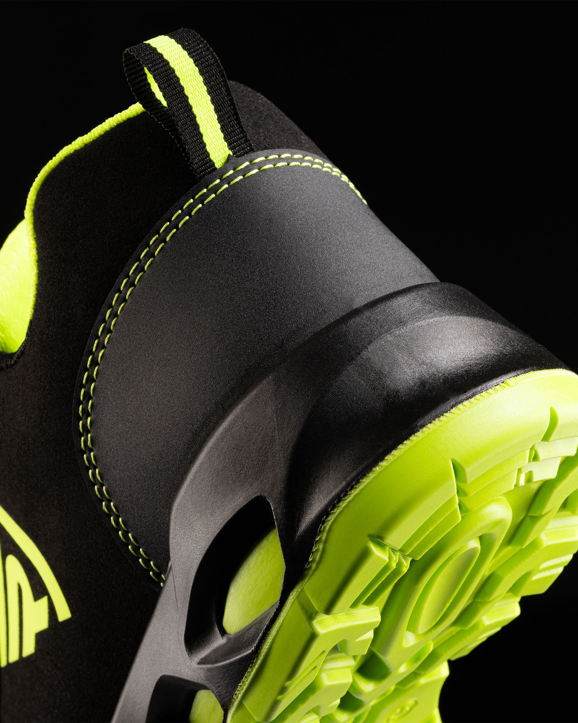 Un primer plano de un zapato negro con suela verde.