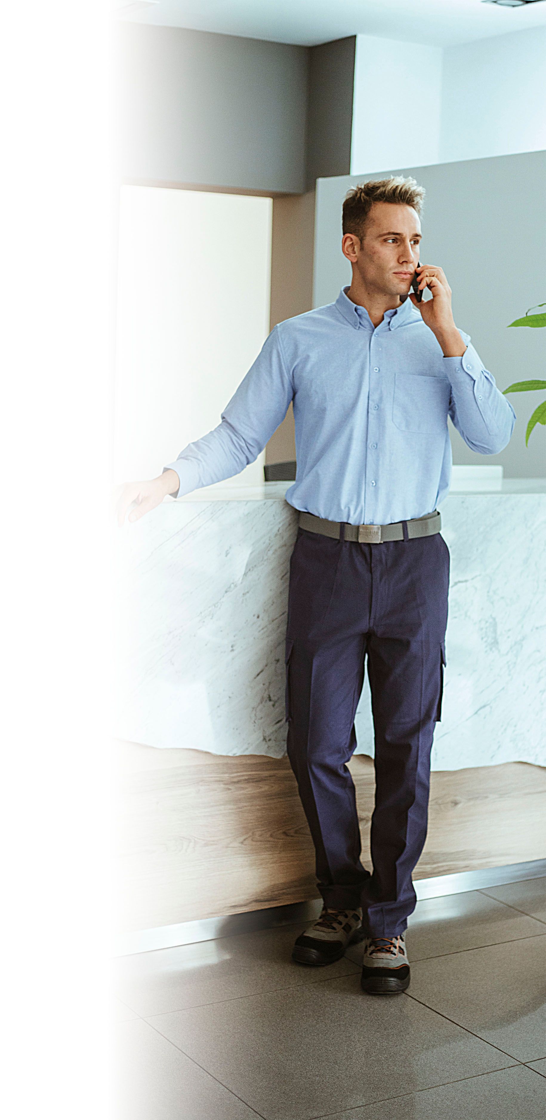 Un hombre está parado frente a un mostrador hablando por un teléfono celular.