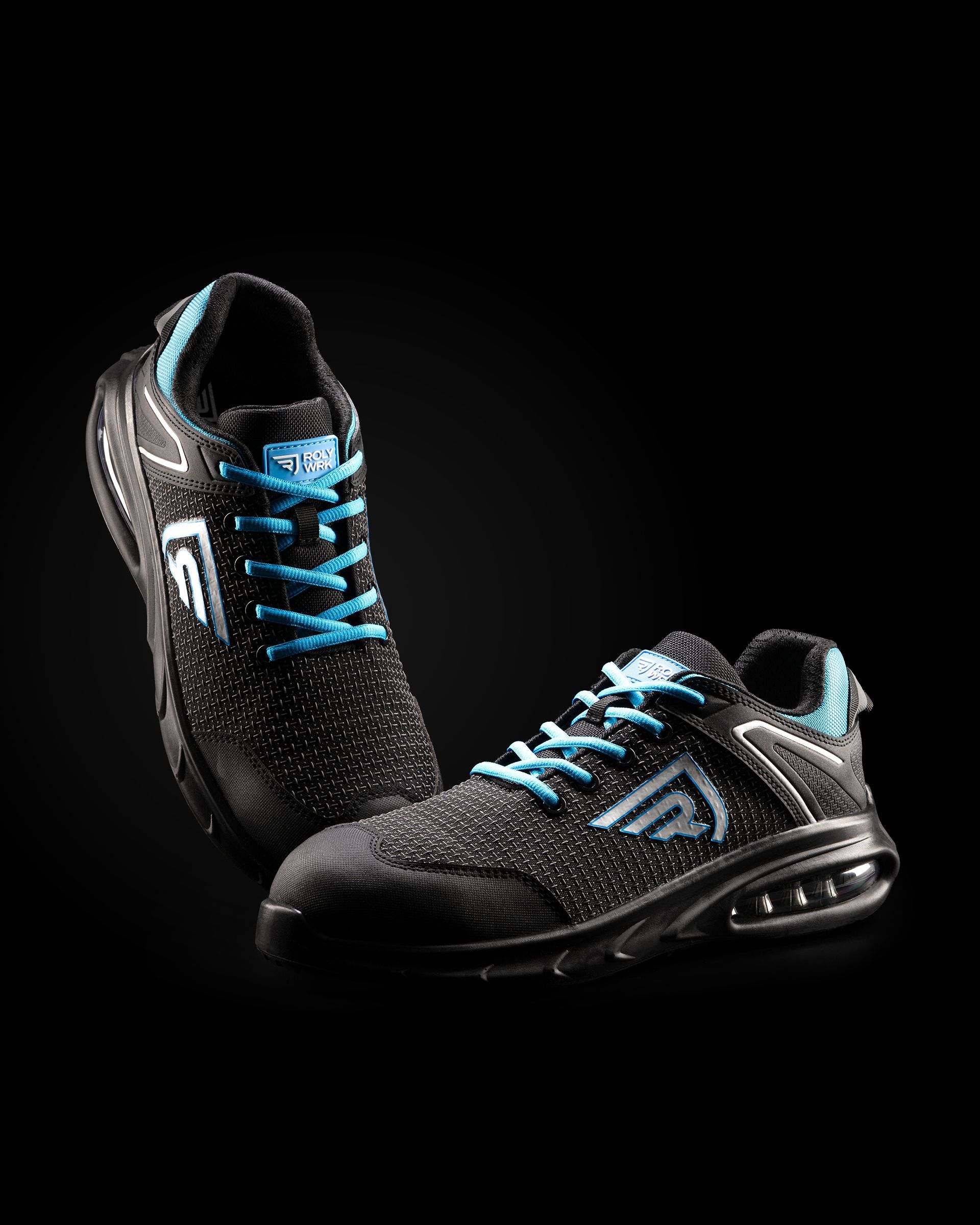 Un par de zapatos de seguridad negros y azules sobre un fondo negro.