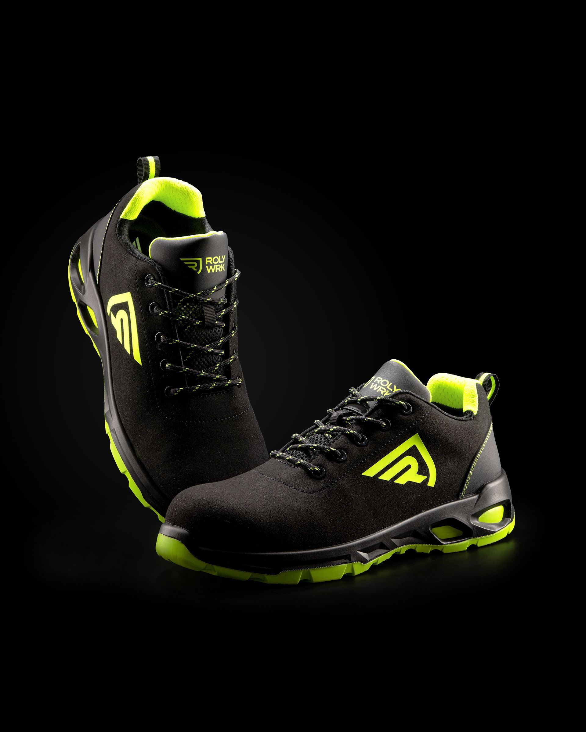 Un par de zapatos de seguridad de color negro y amarillo neón sobre un fondo negro.