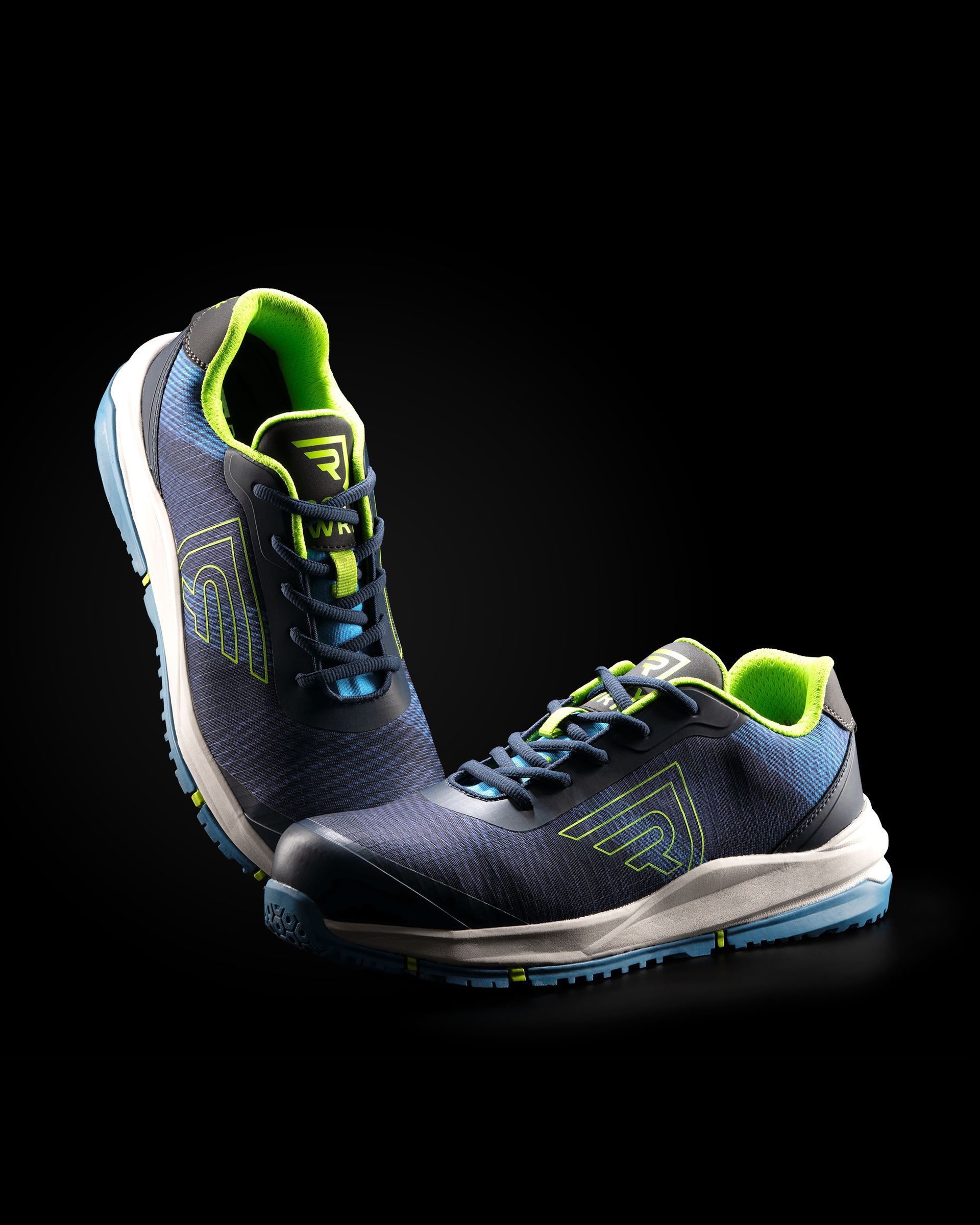 Un par de zapatos de seguridad azules y verdes sobre un fondo negro.