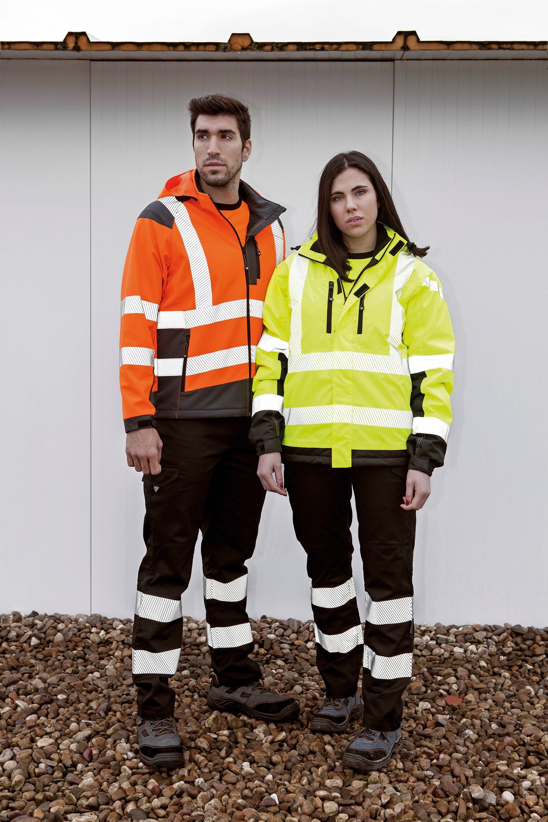 Un hombre y una mujer de pie uno al lado del otro con chalecos de seguridad.