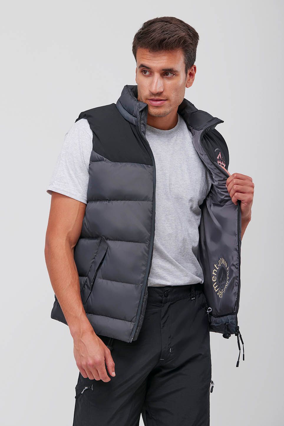 Un hombre lleva un chaleco gris y pantalones negros.