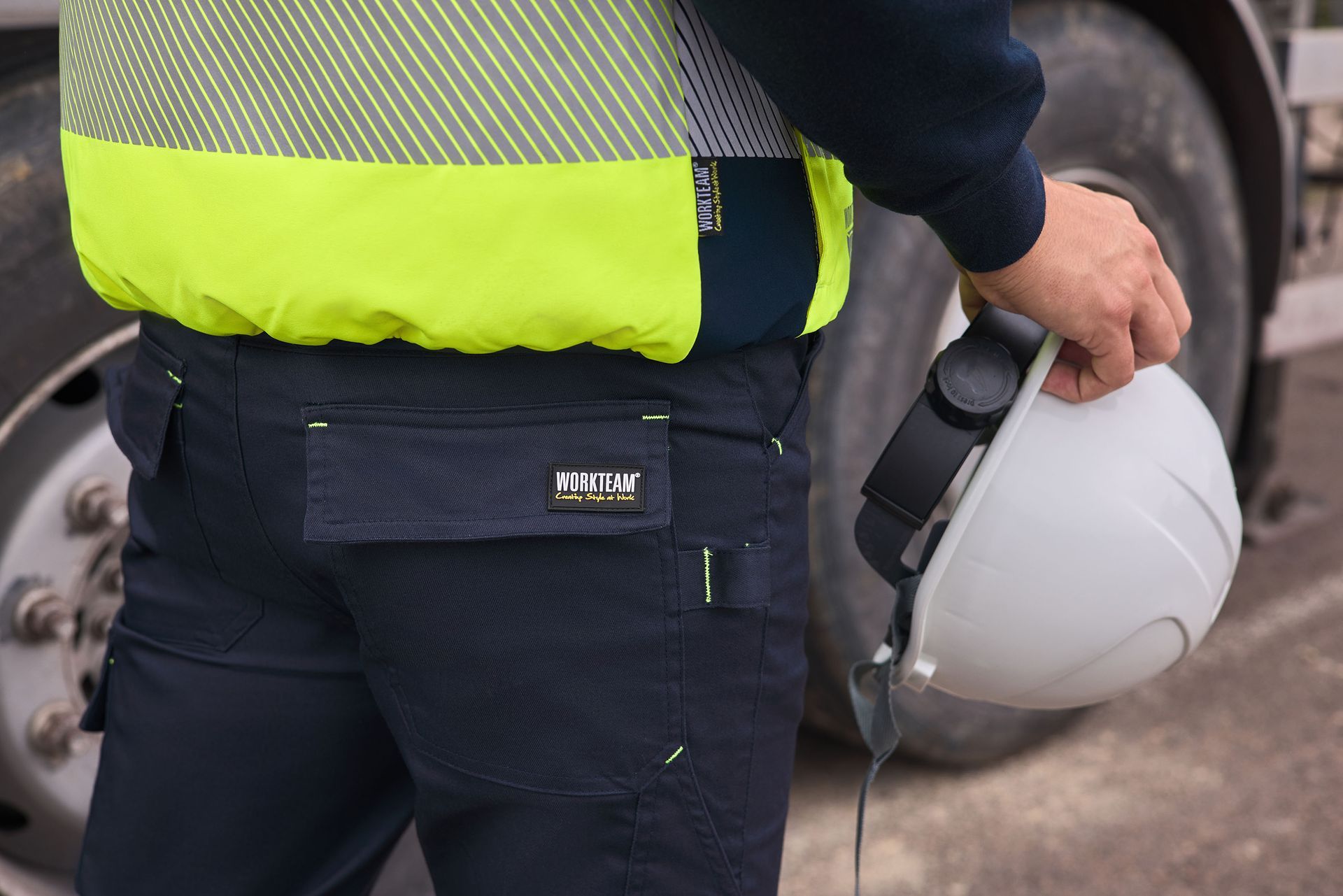 Un hombre con un chaleco amarillo sostiene un casco blanco.