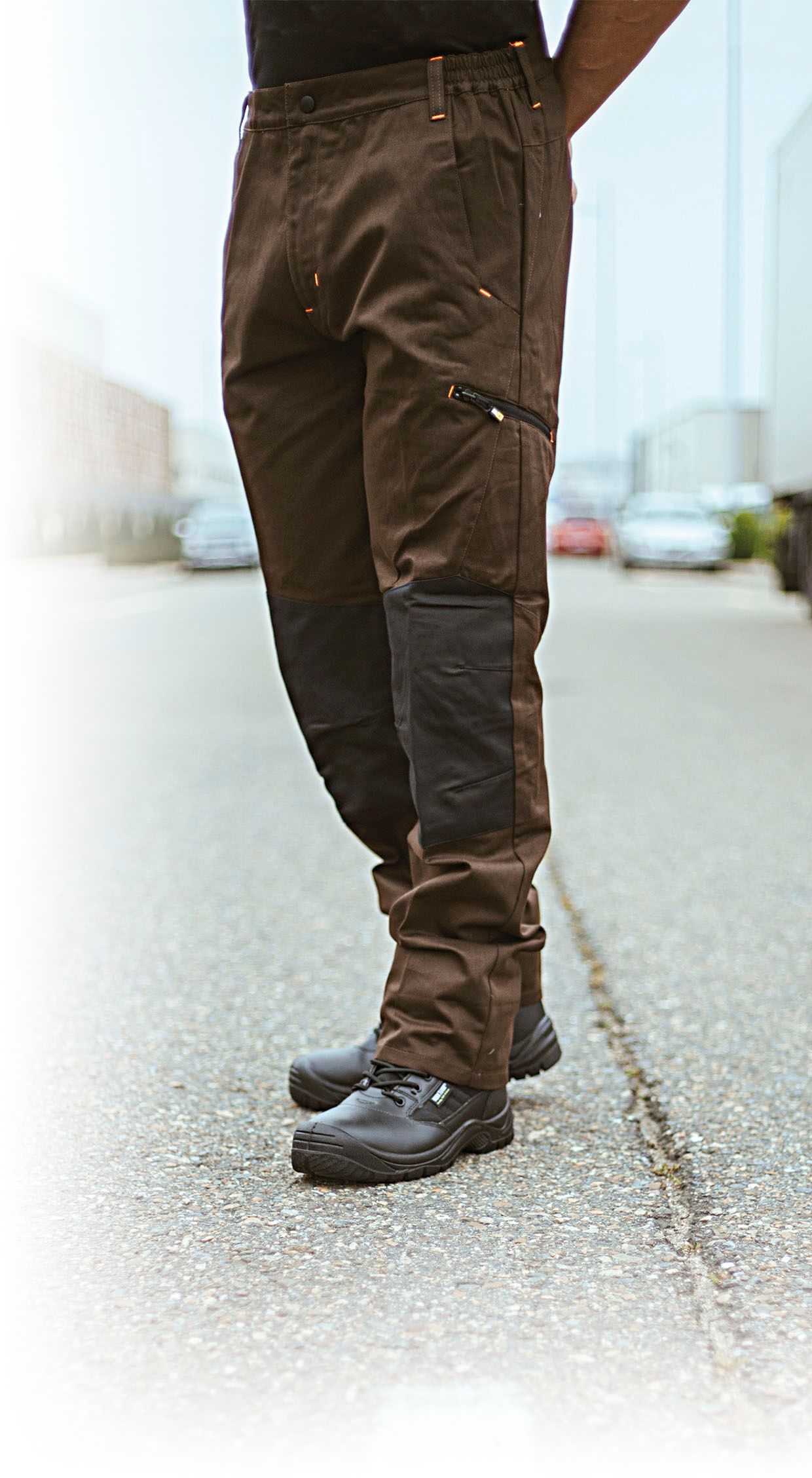 Un hombre que lleva pantalones marrones y zapatos negros está parado en una acera.