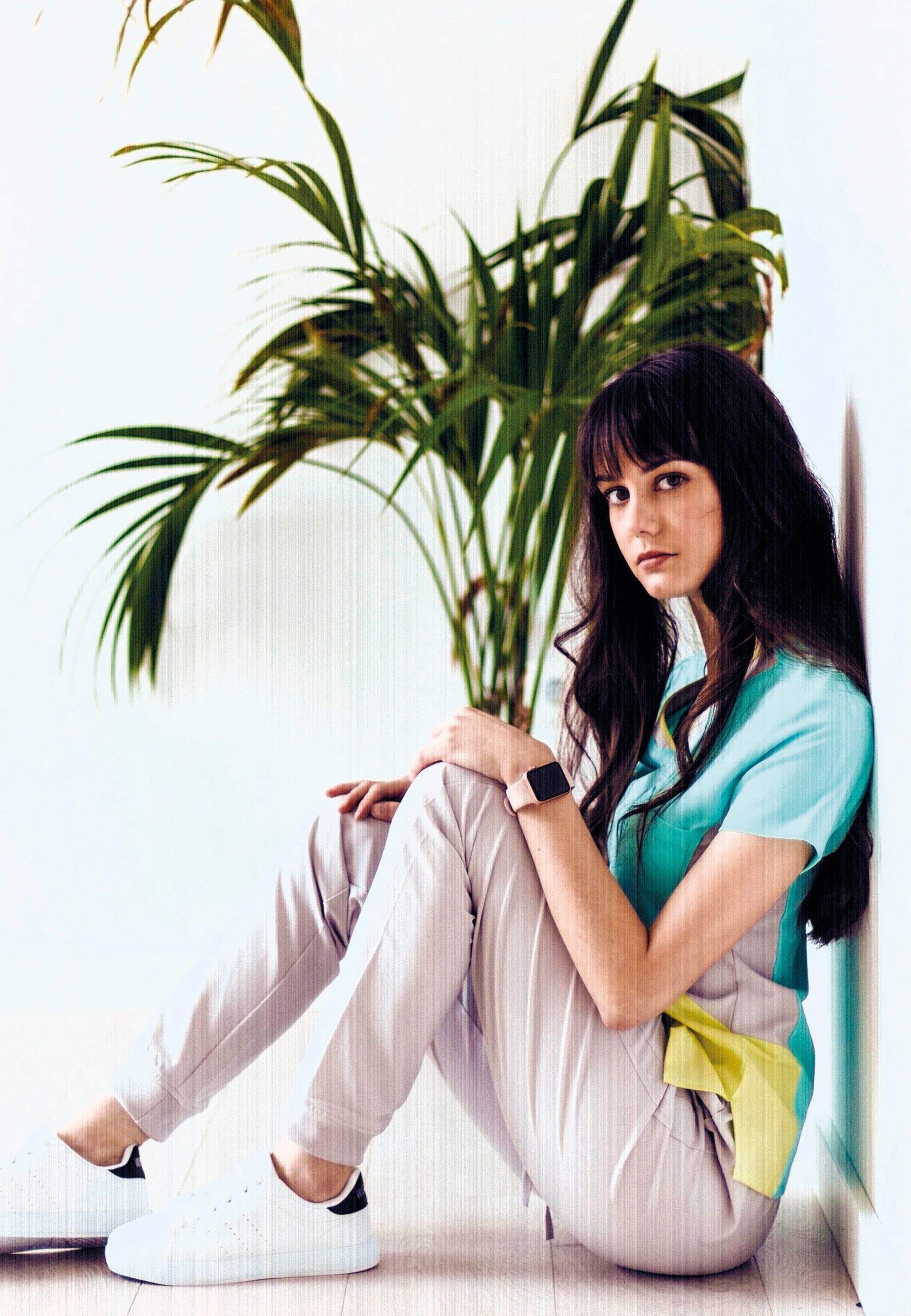 Una mujer está sentada en el suelo junto a una palmera.