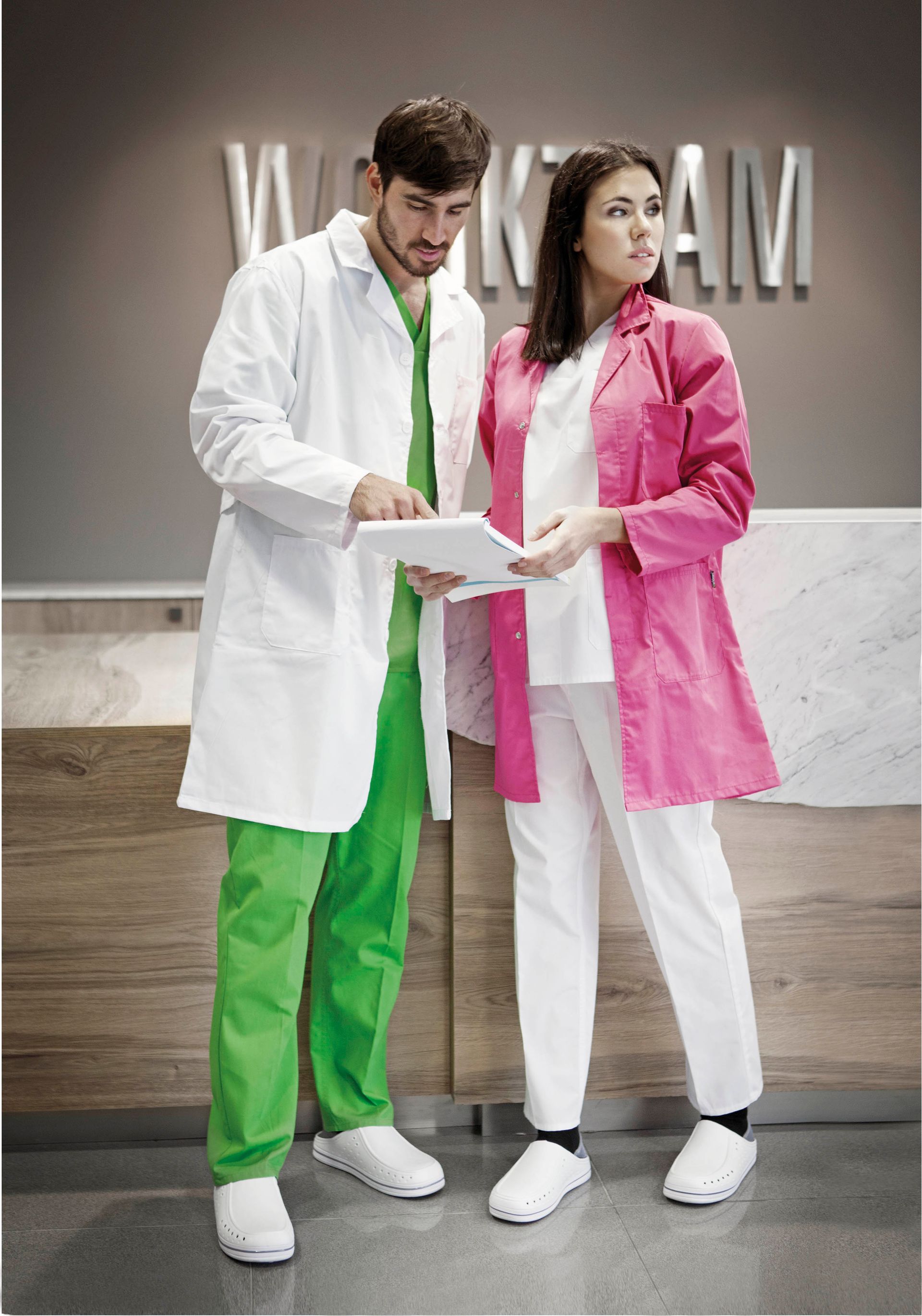 Un hombre y una mujer con batas de laboratorio miran una tableta.