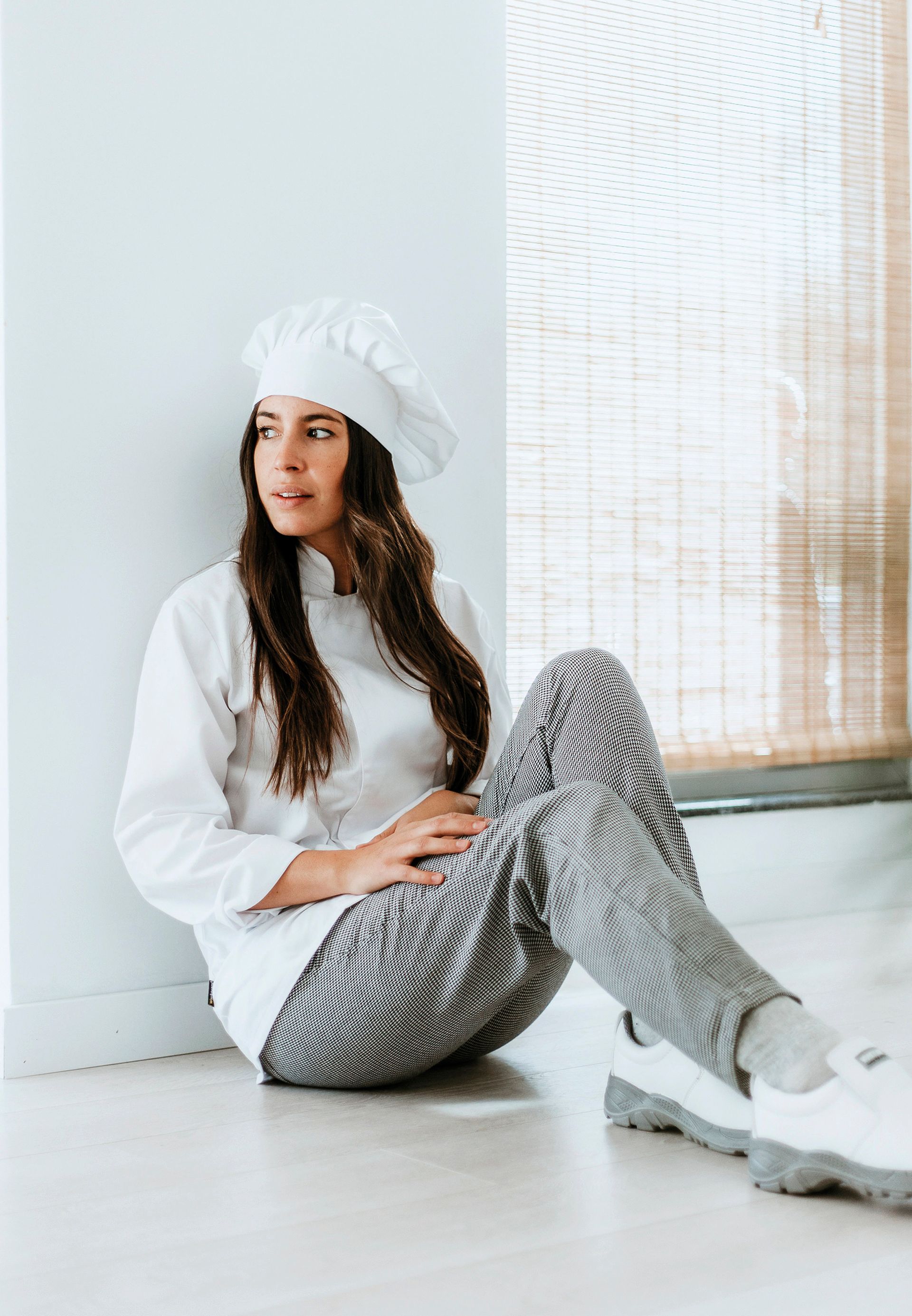 Una mujer con un gorro de chef está sentada en el suelo.