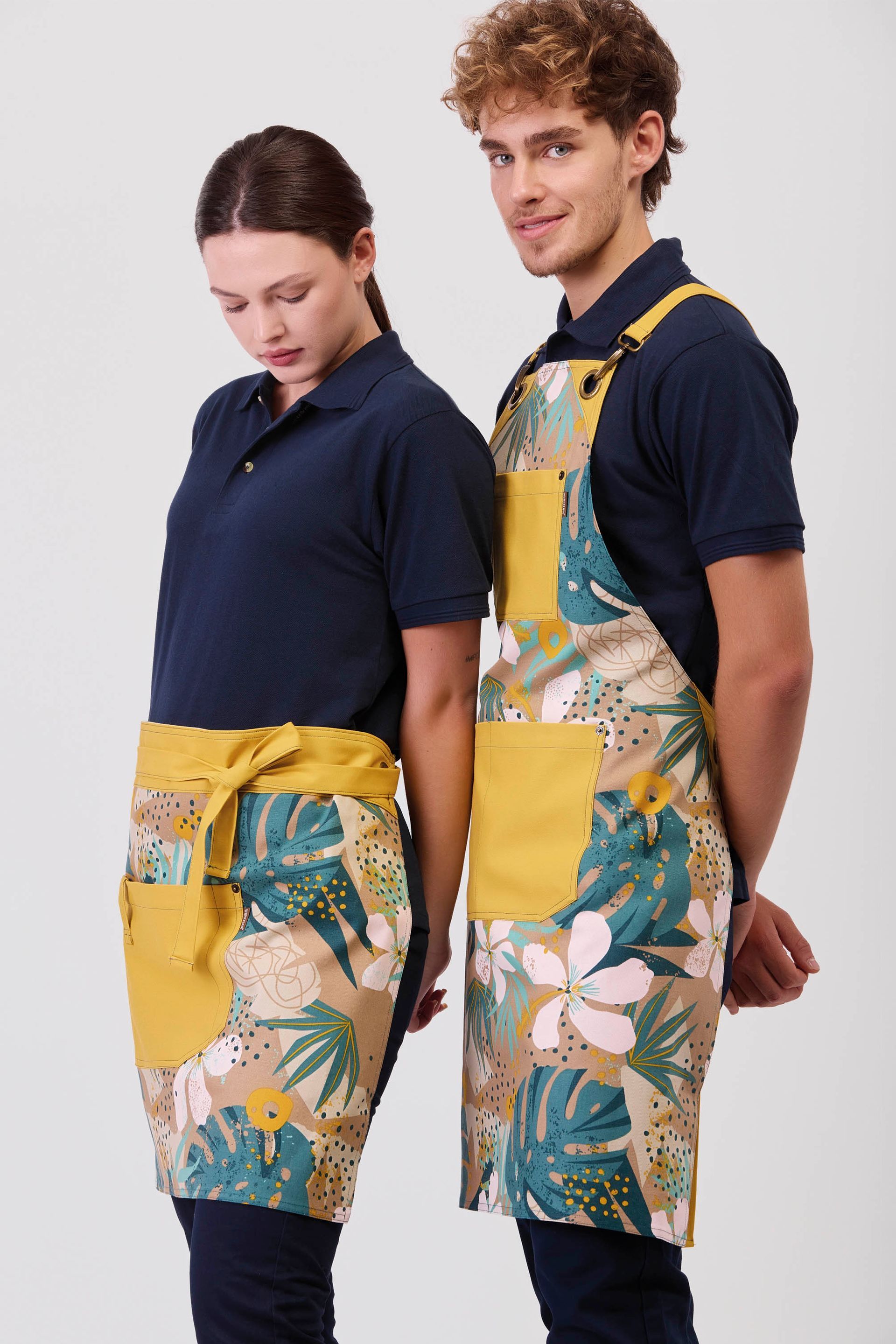 Un hombre y una mujer que llevan delantales están de pie uno al lado del otro.