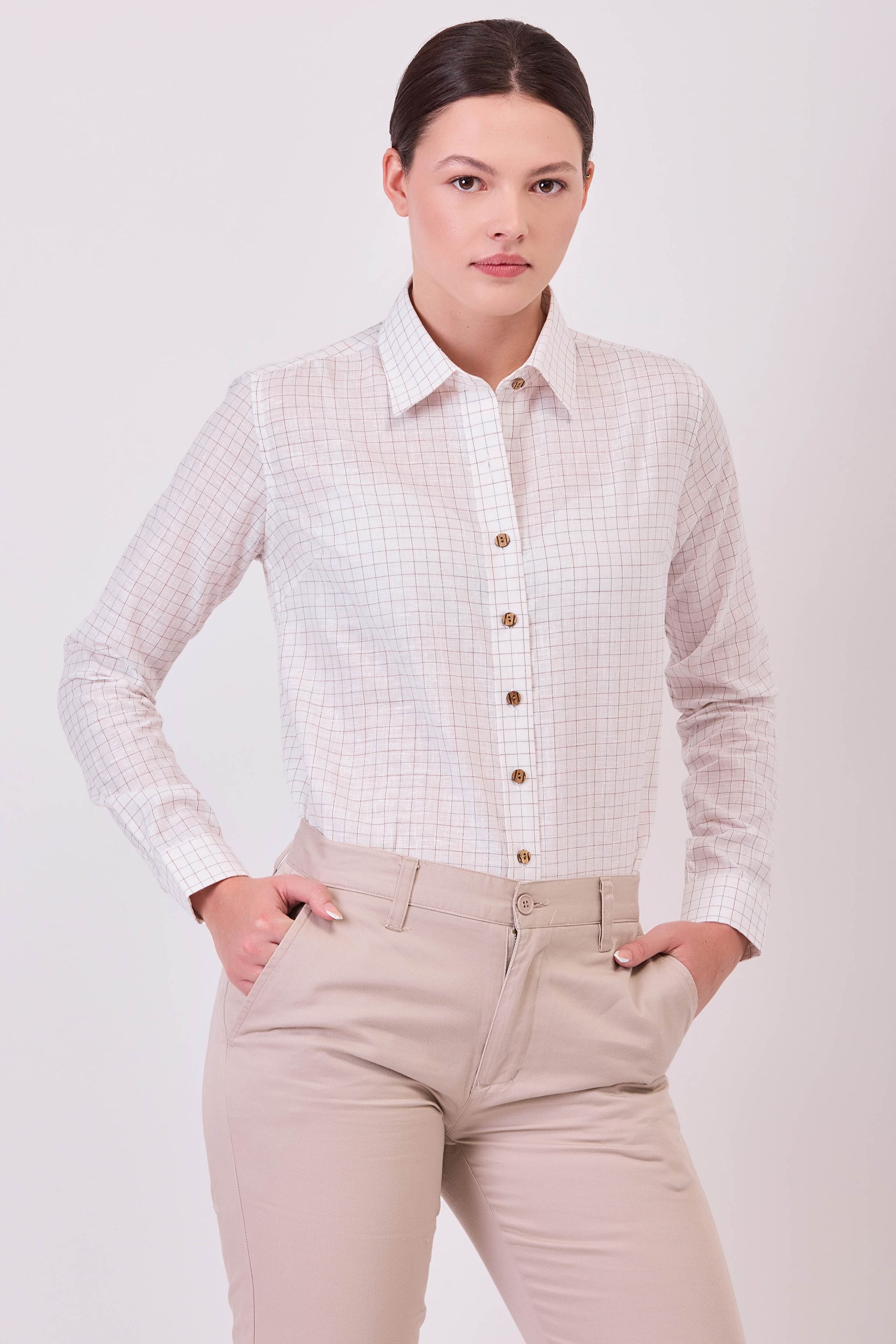 Una mujer lleva una camisa blanca y pantalones caqui.